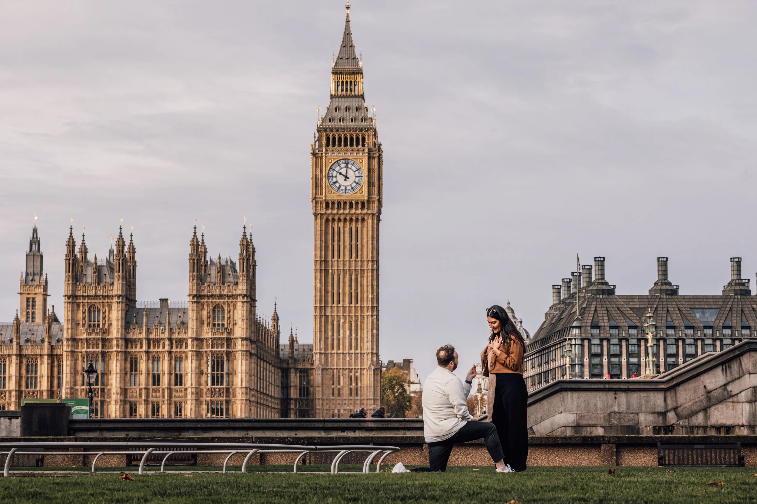 A man proposes marriage to a woman in front of Big Ben and the Houses of Parliament in London, England.