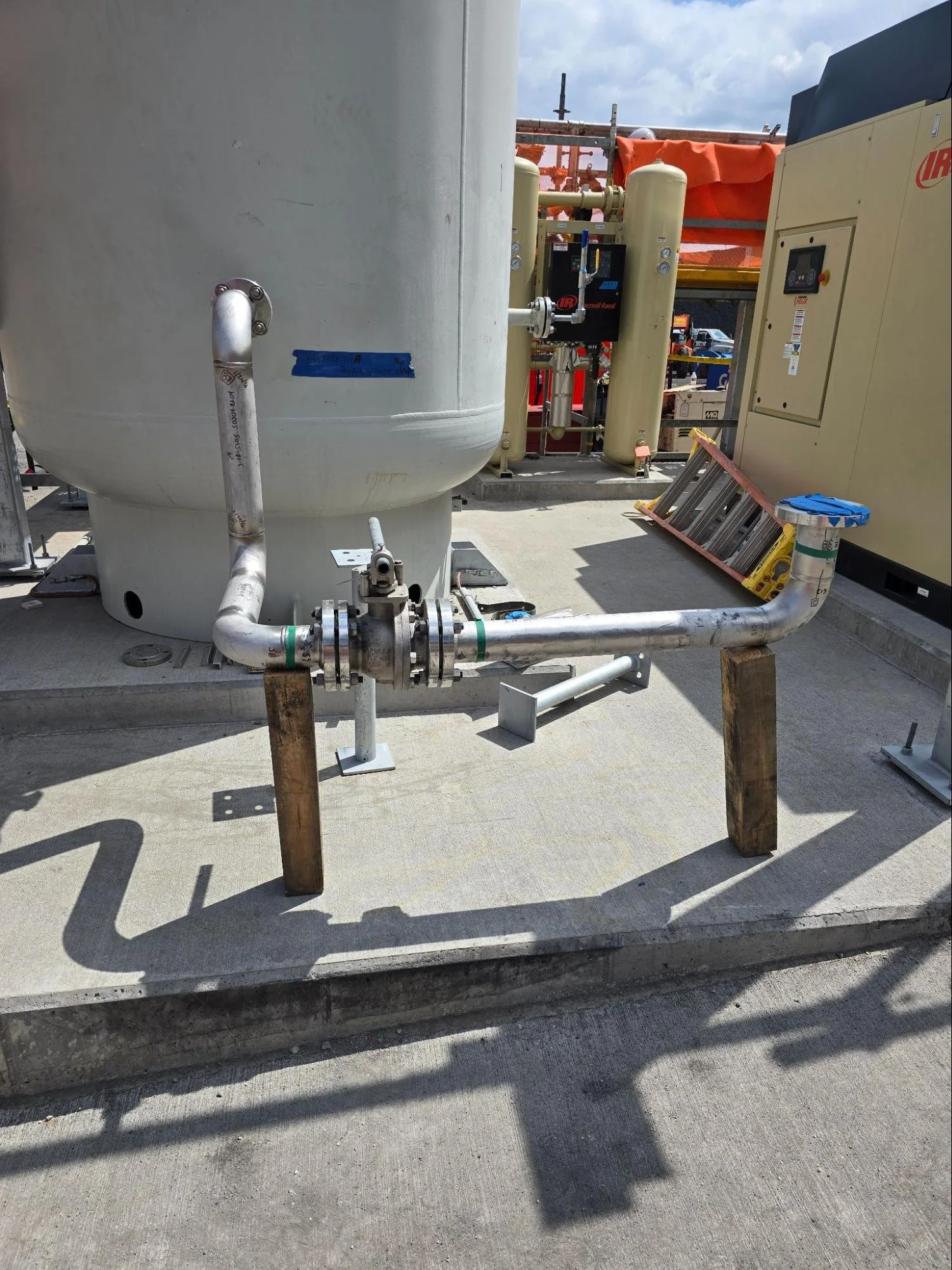 Stainless steel process piping supported by structural steel framing connects to an industrial process vessel at a Sundt job site during mechanical system installation by Melting Point LLC in SC.