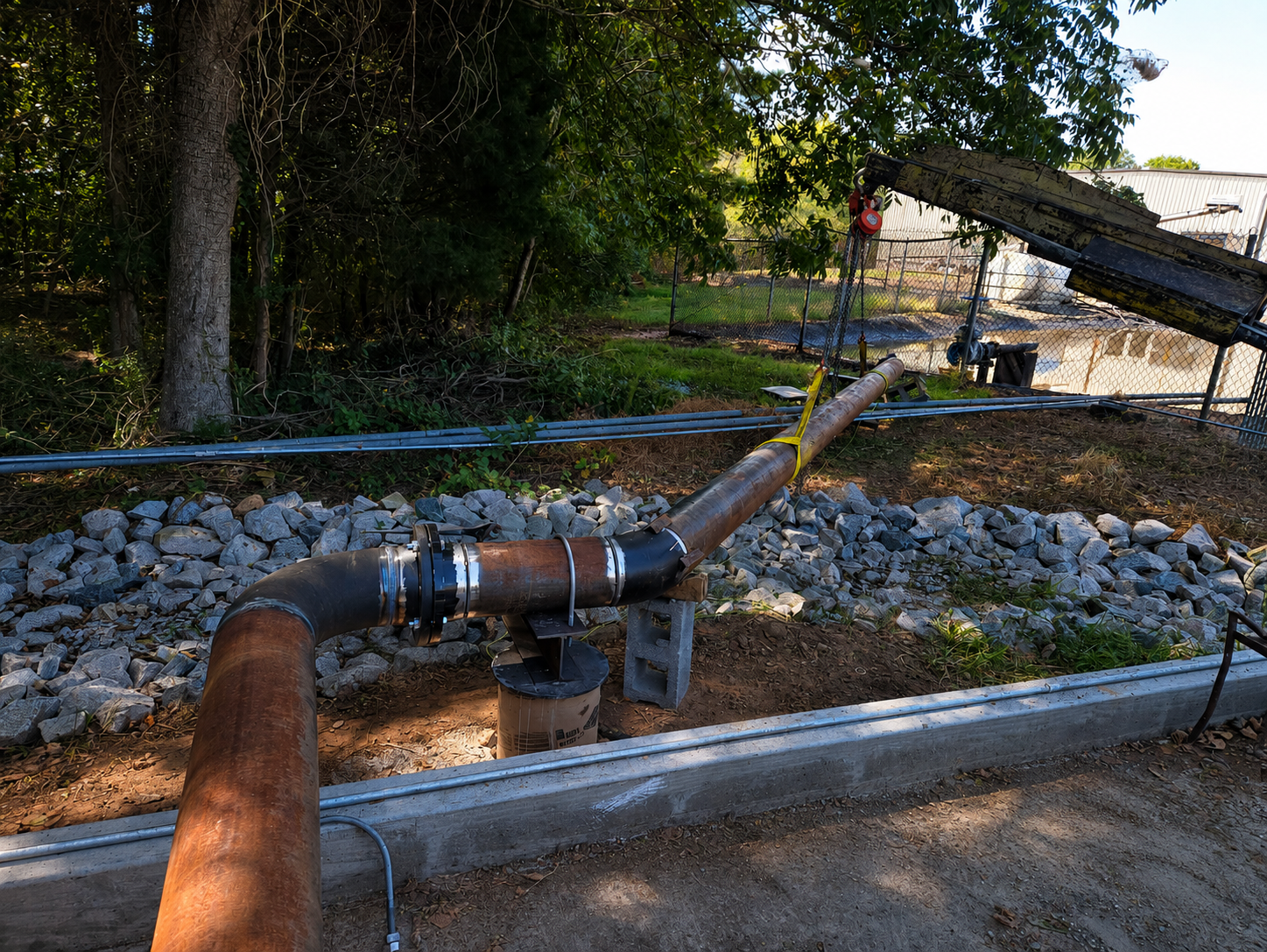 Industrial process piping installation by Melting Point LLC, connecting a storage tank to welded carbon steel piping, demonstrating expert mechanical piping fabrication and field installation at the FOMAS facility.
