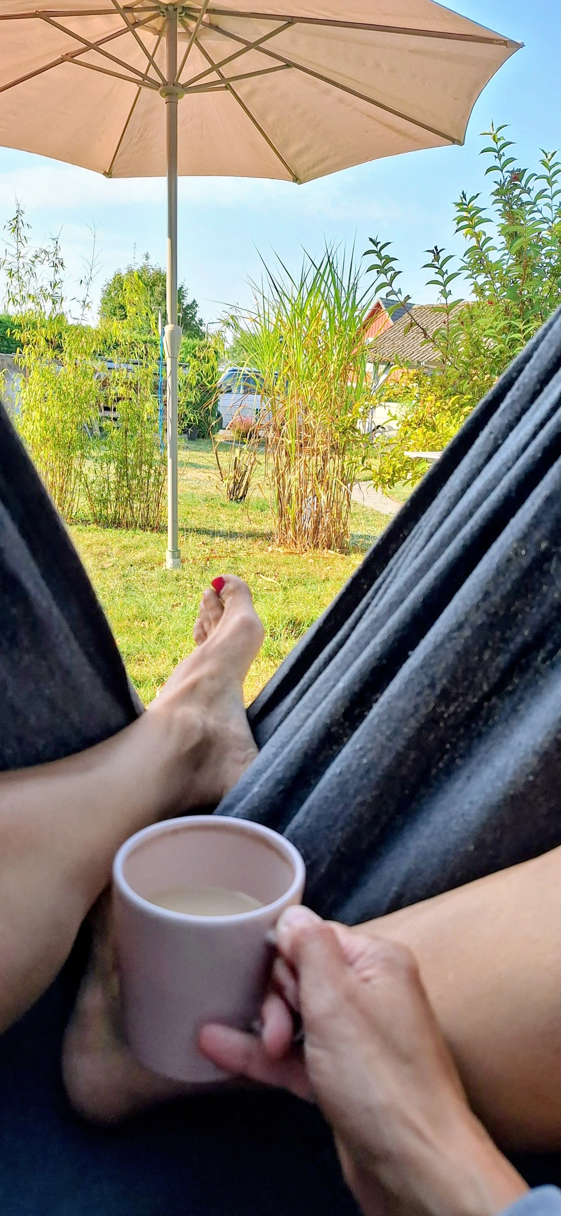 In der Hängematte sitzend mit einem Kaffee in der Hand in den Garten vom UnserGüsterHaus schauend.