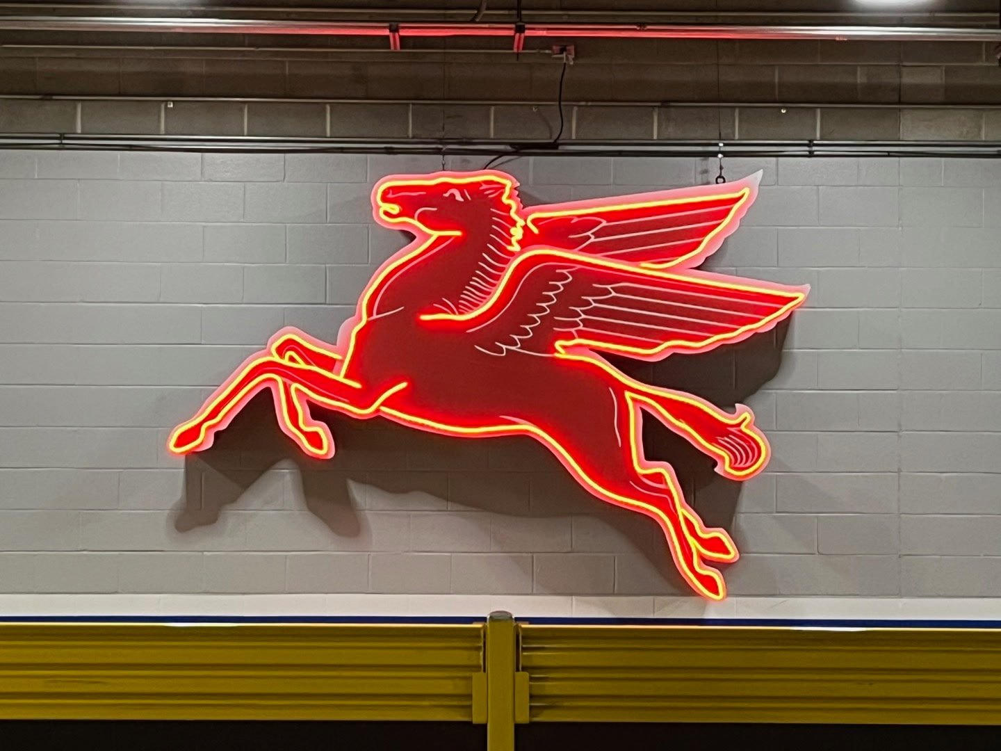 Neon sign of a red Pegasus, the winged horse, mounted on a wall.