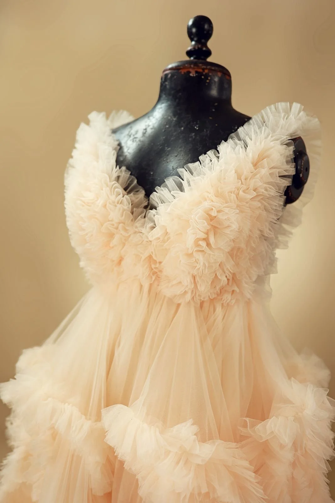 Close up of Champagne-gold beige gown, with fluffy textured tulle skirt, open back, and strappy design