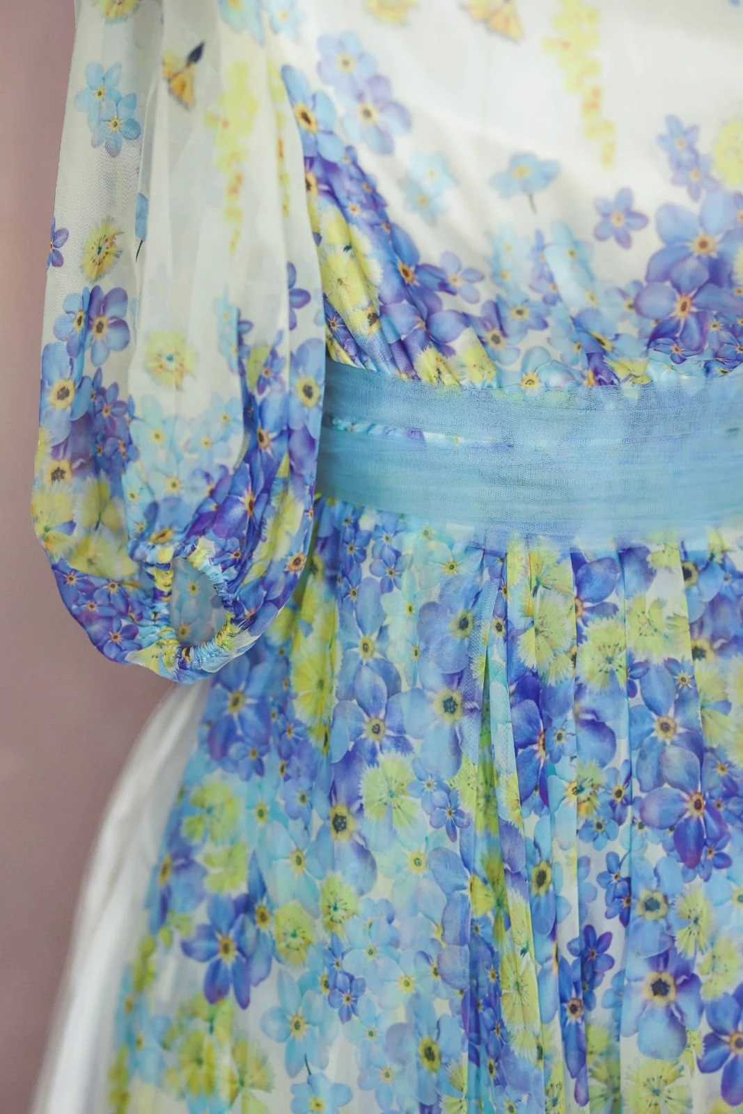 Close up view of a white maxi dress sleeves, showing blue and yellow floral print