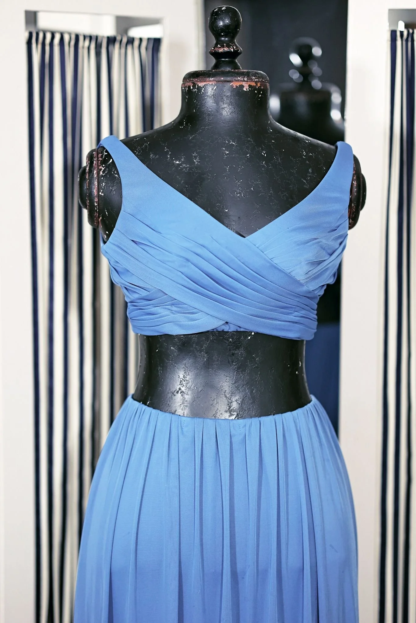 Close up of two-piece dress, featuring a fabric top with a tie at the back and a floor-length skirt