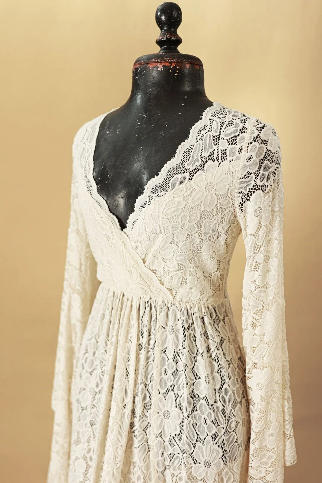 Close up of cream white lace dress, showing floral lace embroidery and V-neck cut