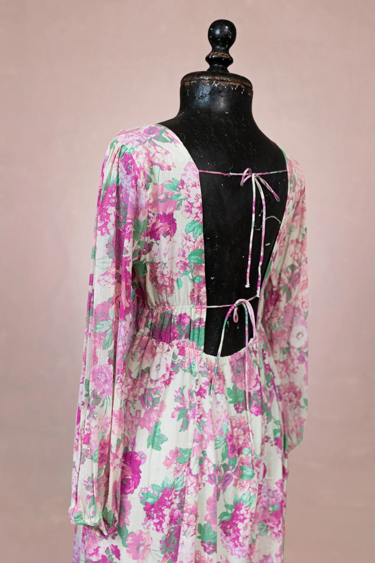 Back view of floral print maternity rental dress, showing open back design