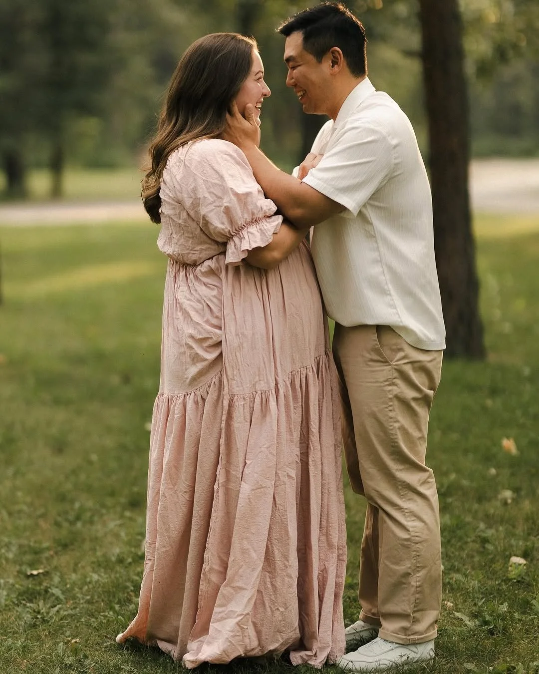 A couple standing next to each other, in an outdoor maternity photoshoot