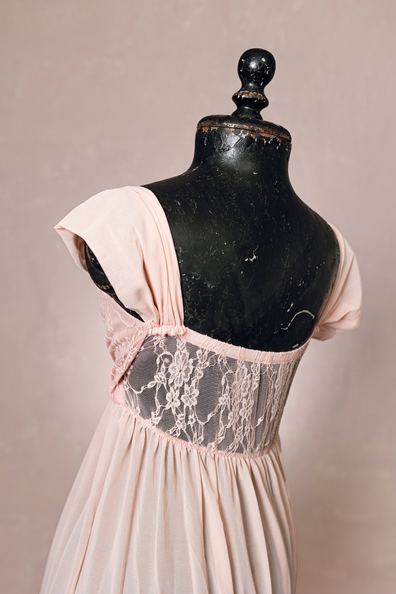 Back view of peach pink rental dress, showing sheer lace back design