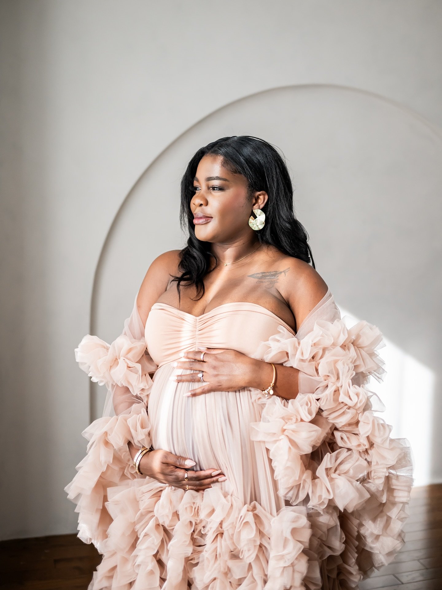 Portrait of a pregnant woman wearing a ruffled tulle dusty rose gown, in Calgary maternity studio session
