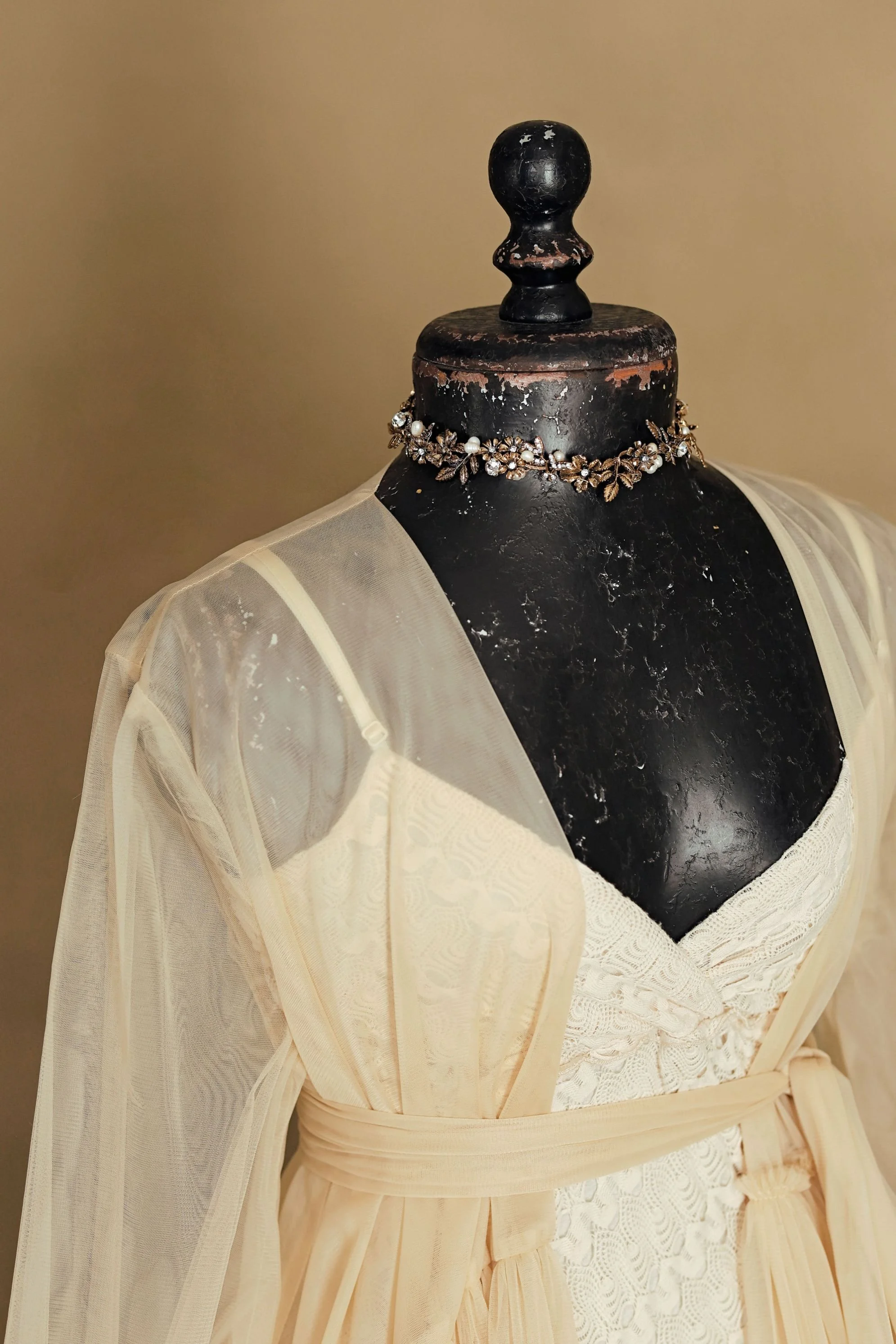 Close up of yellow tulle floor-length robe combined with a white lace sleeveless dress, and added jewellery necklace