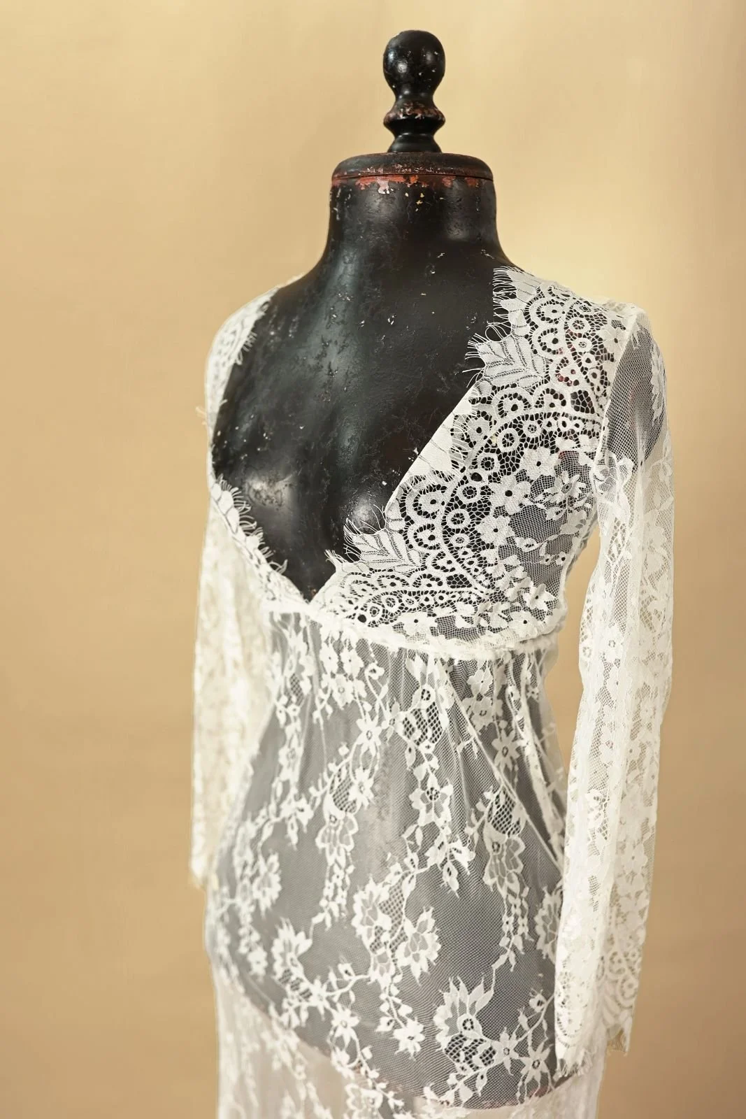 Close up of white sheer transparent lace dress, with floor-length skirt, v-neck, and long sleeves
