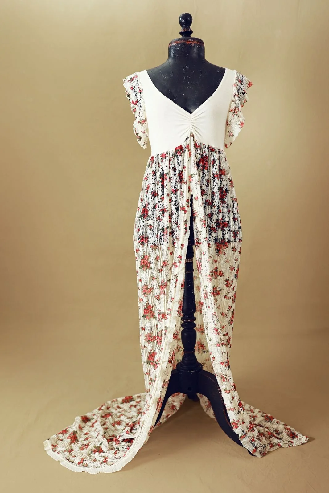 A maternity photoshoot bodycon dress with white cinched top and floor length lace skirt with red floral print