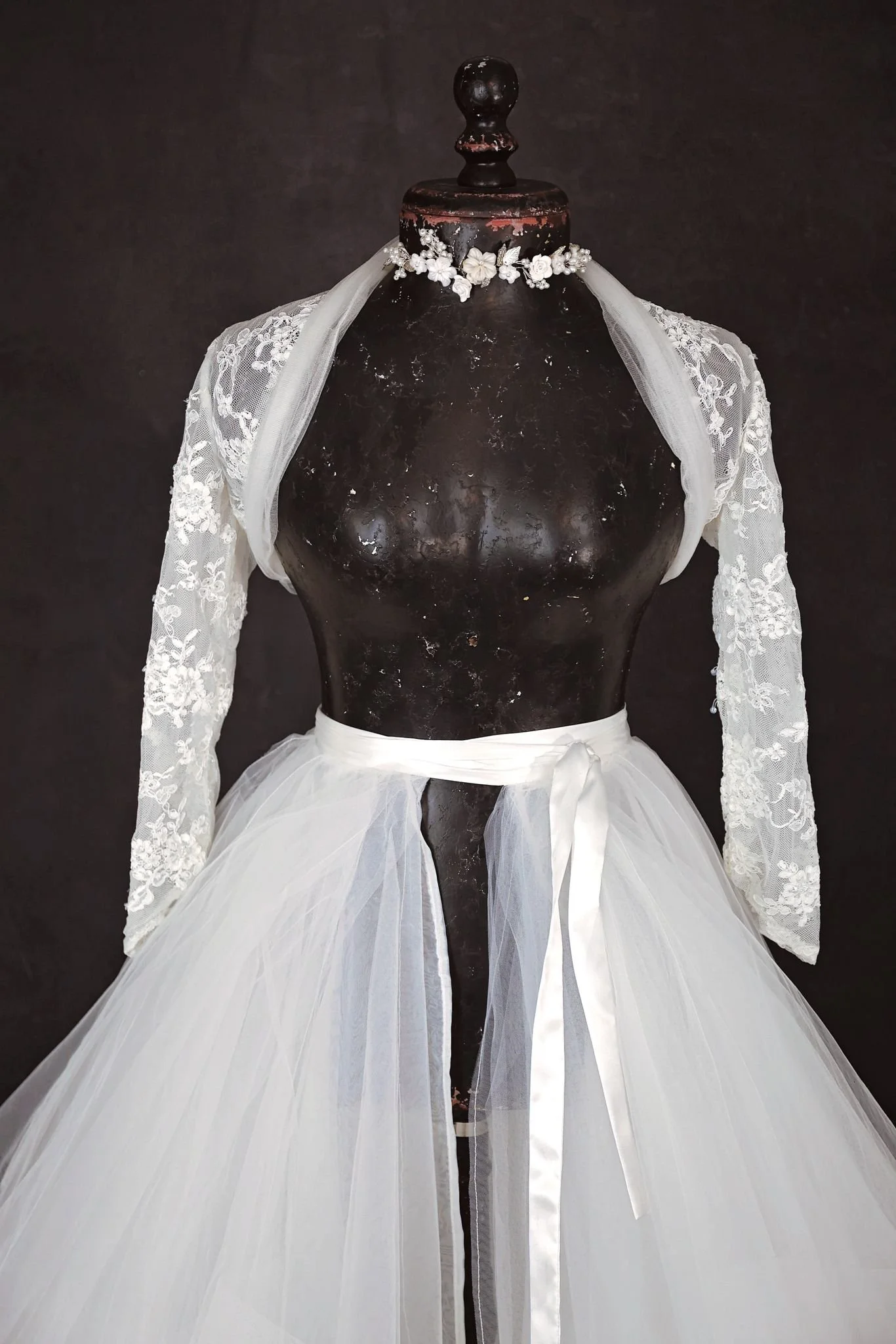 Close up of white layered textured puffy tulle skirt and white lace jacket, with silver jewellery ribbon