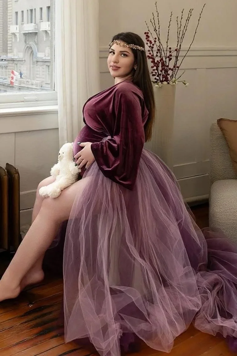 A pregnant woman wearing a Christmas family photoshoot maternity outfit with a velvet bodysuit and long tulle tail