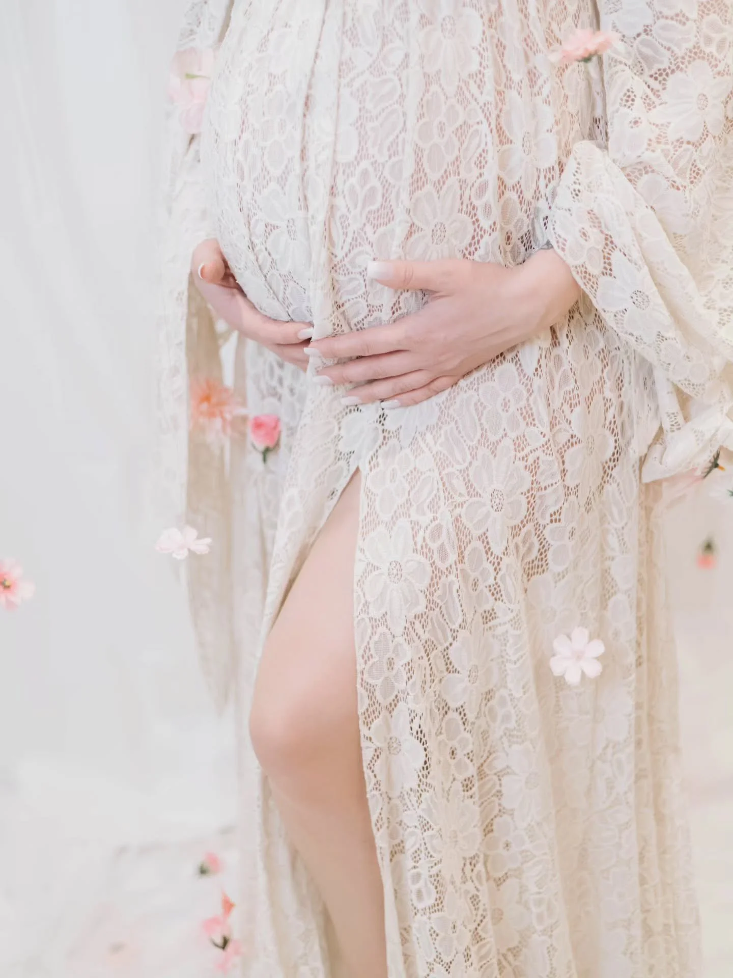 Close up of pregnant woman wearing a cream white lace dress, showing leg opening