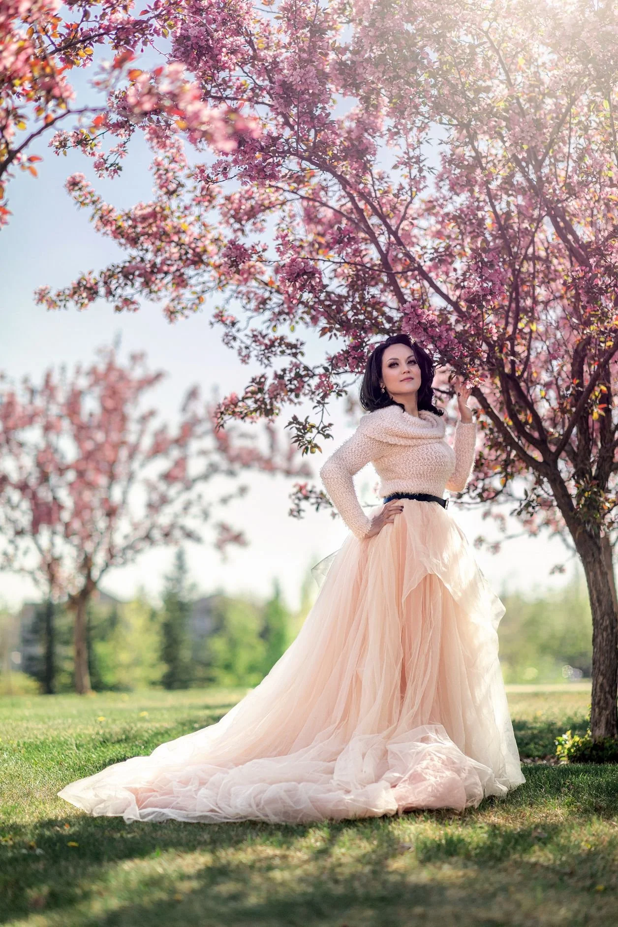 A woman wearing a light peach tulle skirt outfit in an outdoor spring photoshoot in Calgary