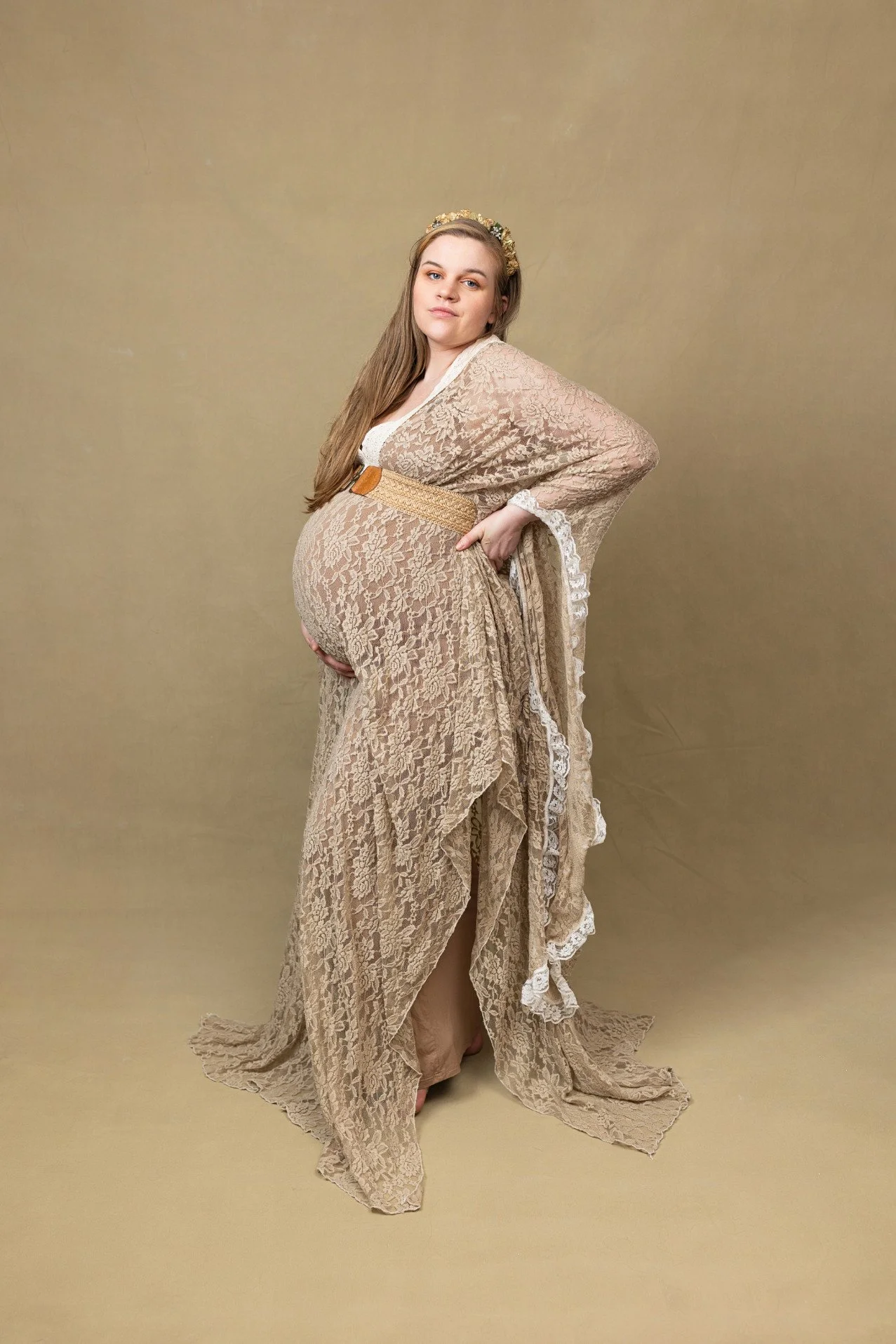 A pregnant woman wearing a khaki lace embroidered maternity photoshoot dress