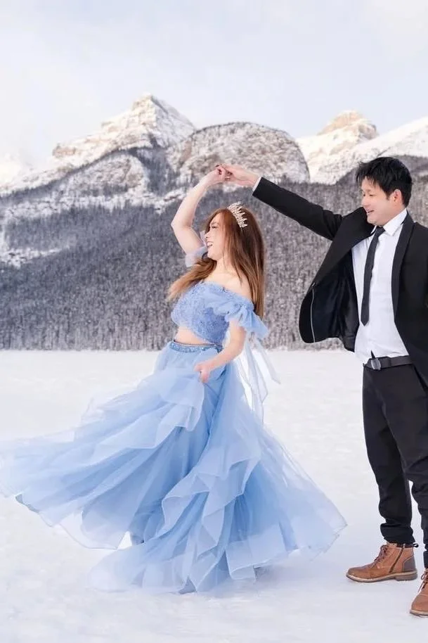Bride and groom-to-be dancing in Lake Louise, with bride wearing sky blue two-piece gown with embellished top