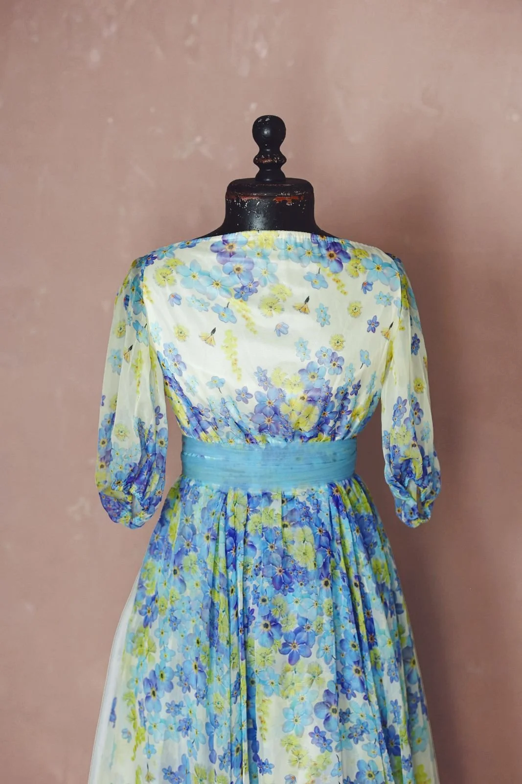 Close up view of a white maxi dress with blue and yellow floral print, for maternity rentals and photoshoots