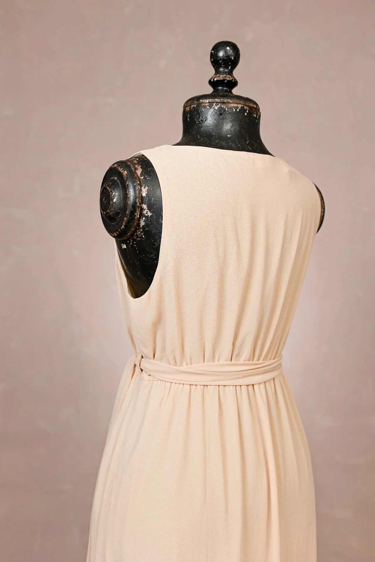 Back view of cream beige maternity rental dress, showing closed back and sleeveless design