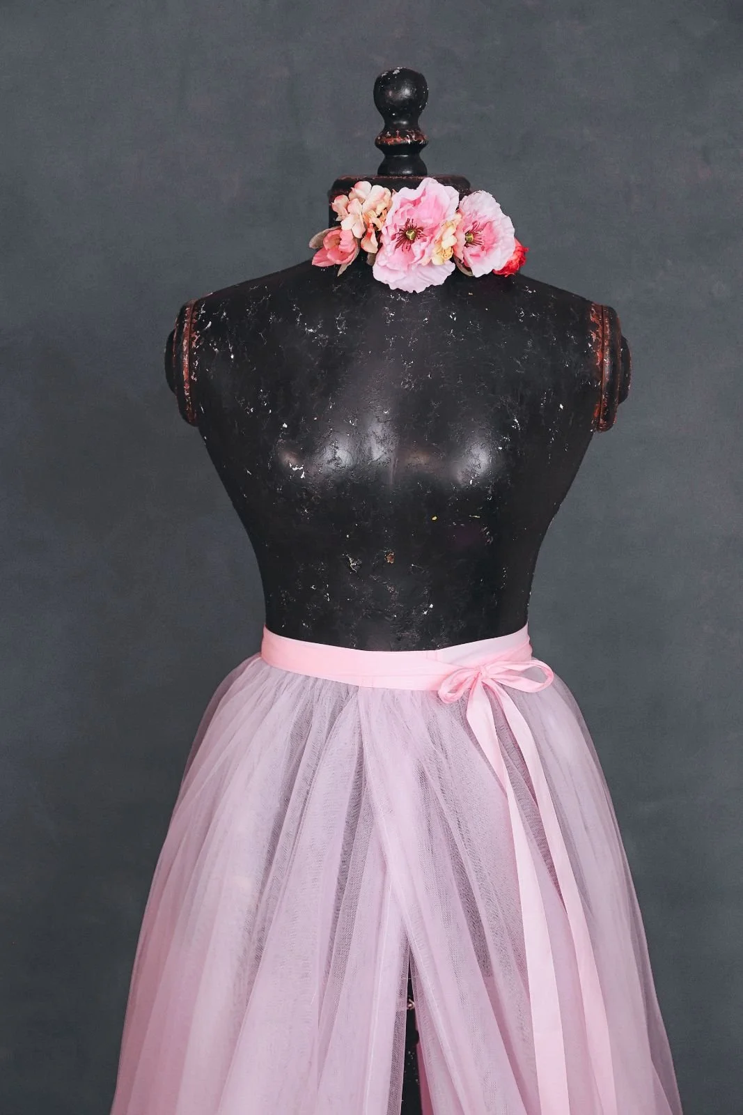 Close up of a light pink tulle skirt, showing a flower ribbon that can be added to any outfit