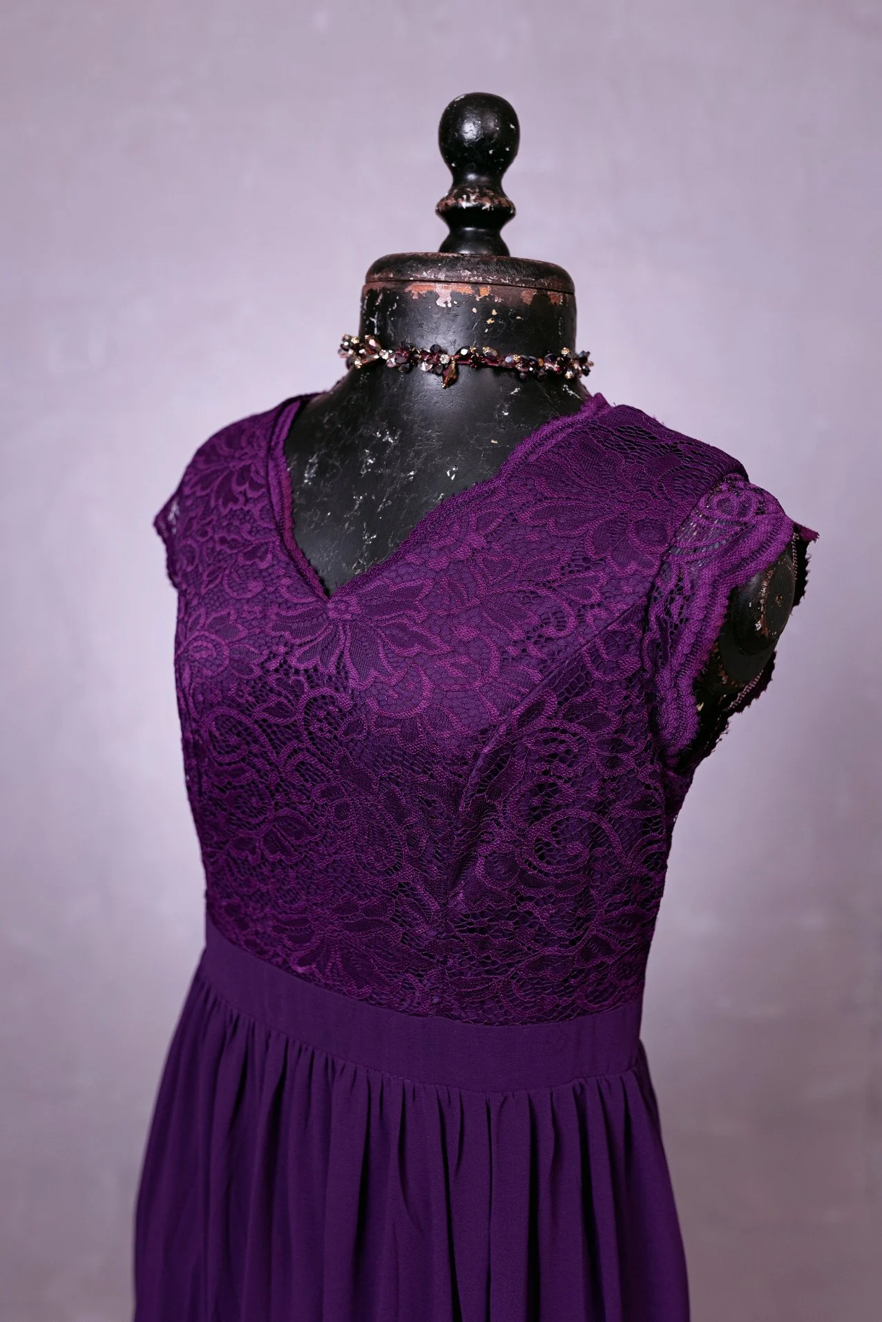 Close up of dark purple sleeveless dress with lace corset and V-neck cut, for rent in Calgary