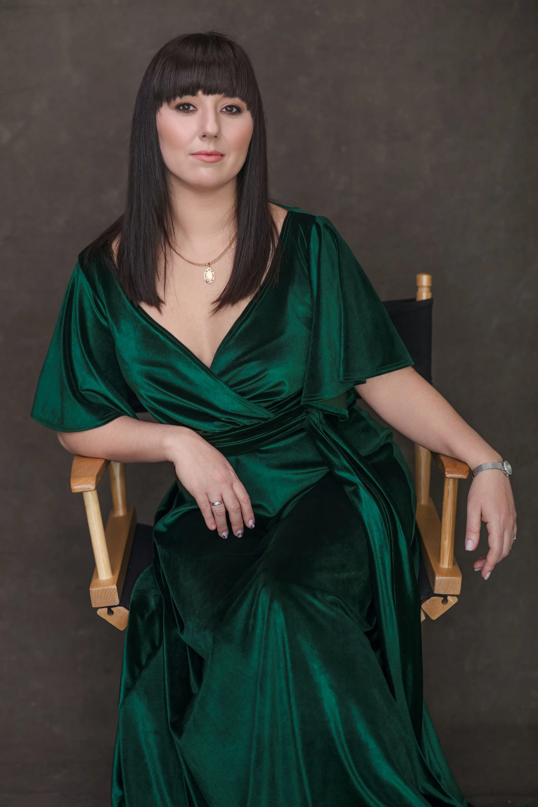 Woman in a green velvet V-neck dress, posing in an indoor studio photoshoot in Calgary