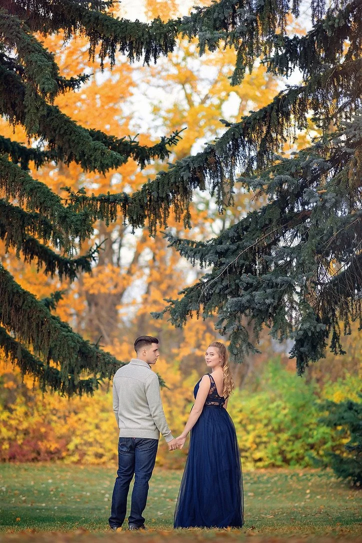 A man standing with a pregnant woman that is wearing a navy blue tulle photoshoot gown