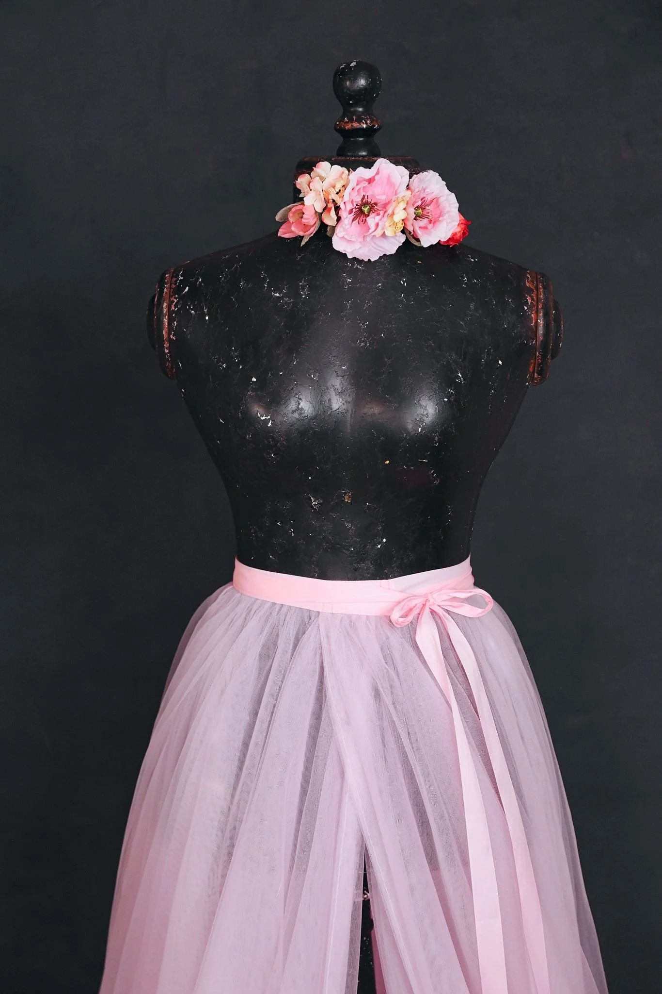 Close up of a light pink tulle skirt, showing a flower ribbon that can be added to any outfit