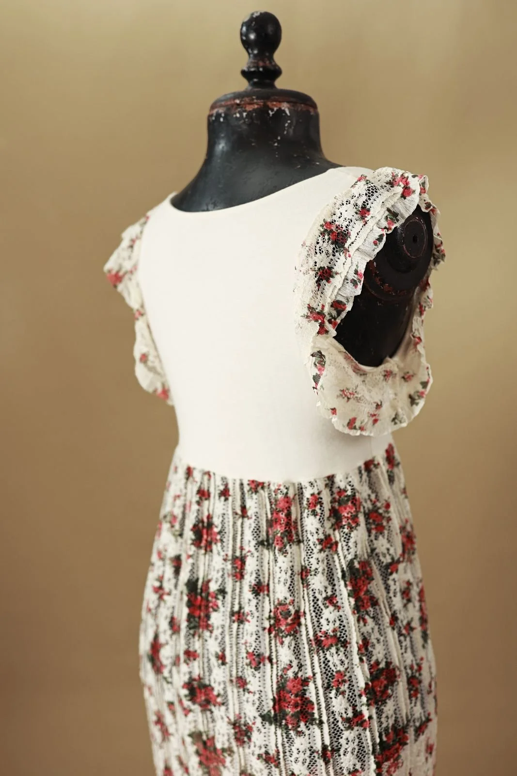 Back view of maternity photoshoot bodycon dress with white cinched top and floor length lace skirt with red floral print