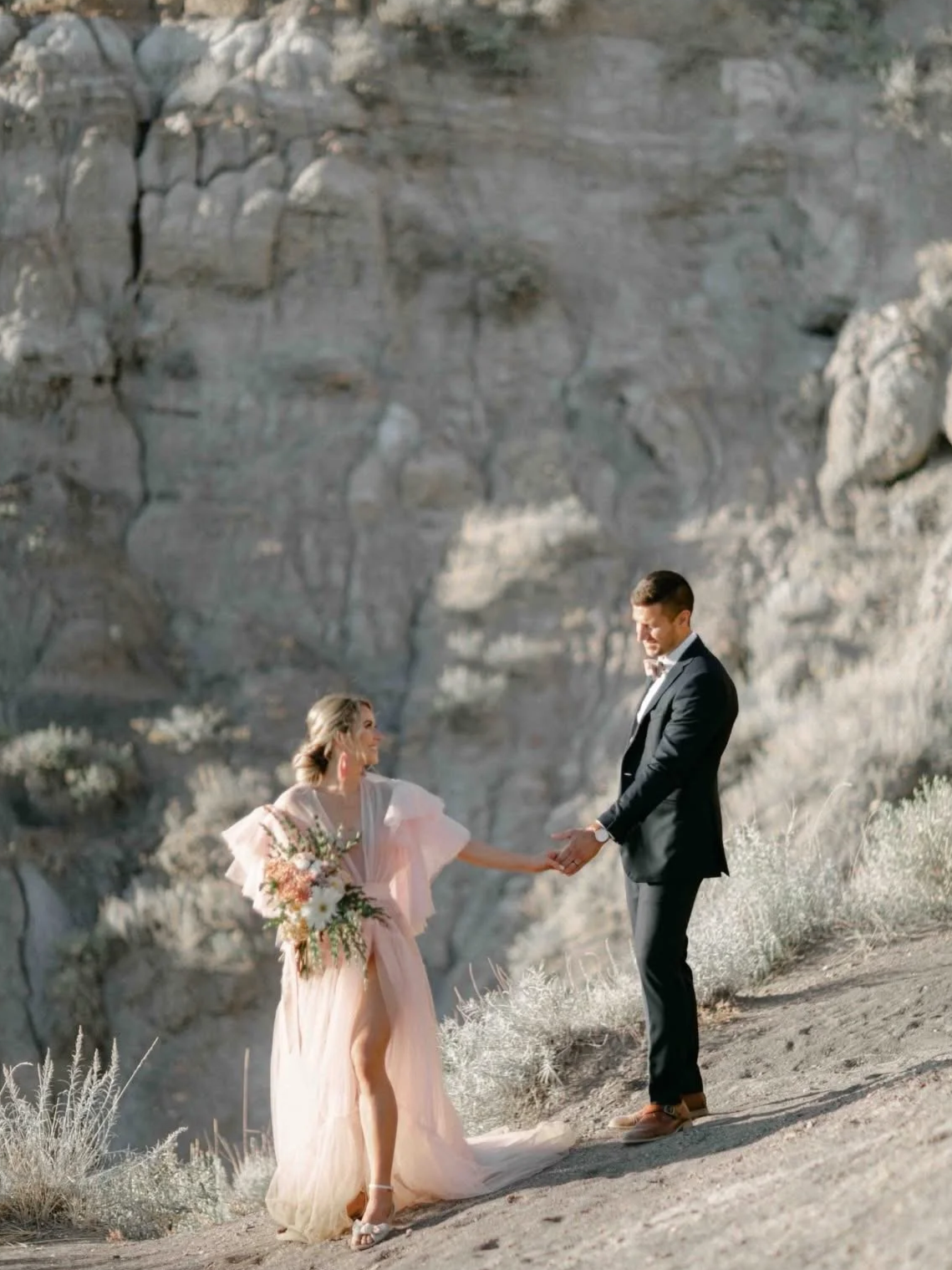 A woman in Drumheller Alberta wearing a fluffy pink gown robe to a bridal photoshoot, standing with her husband