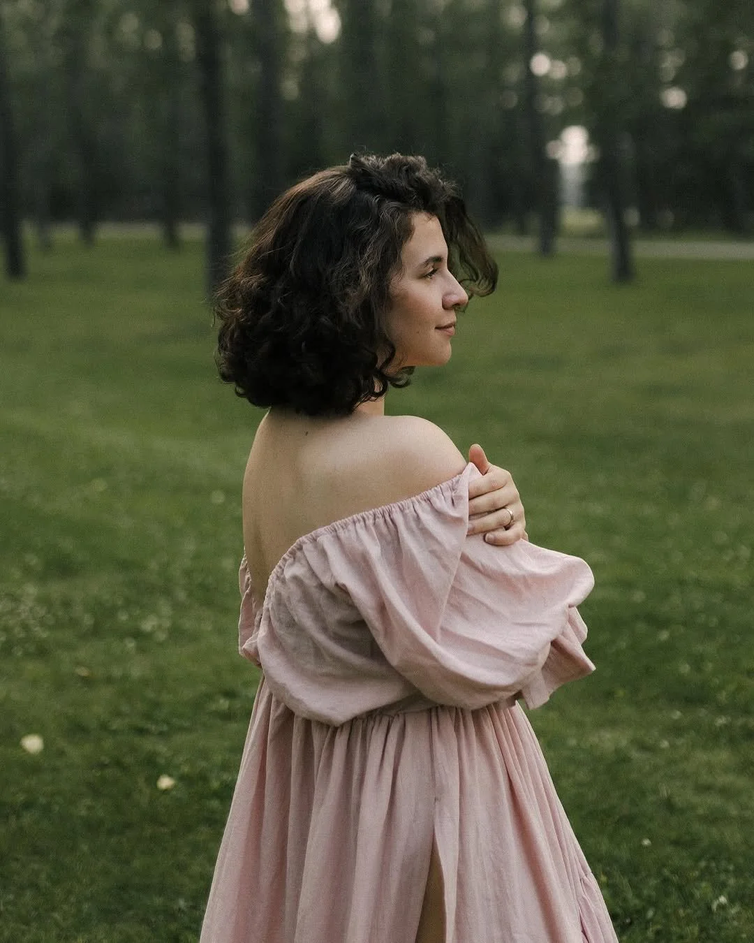 A woman wearing a light pink boho dress with an open back in an outdoor photoshoot in Calgary