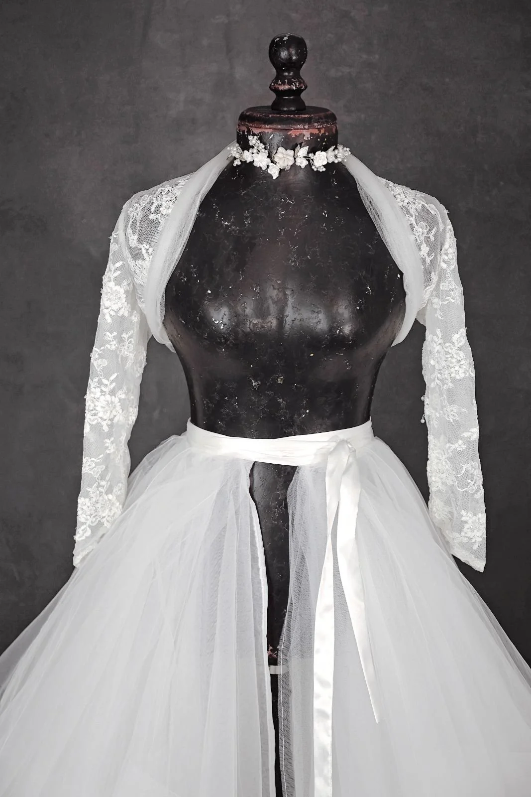 Close up of white layered textured puffy tulle skirt and white lace jacket, with silver jewellery ribbon
