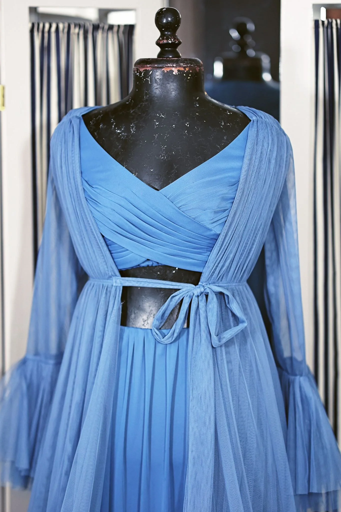 Close up of a sky blue two-piece dress with an open tummy, and an extra long blue tulle robe with long sleeves