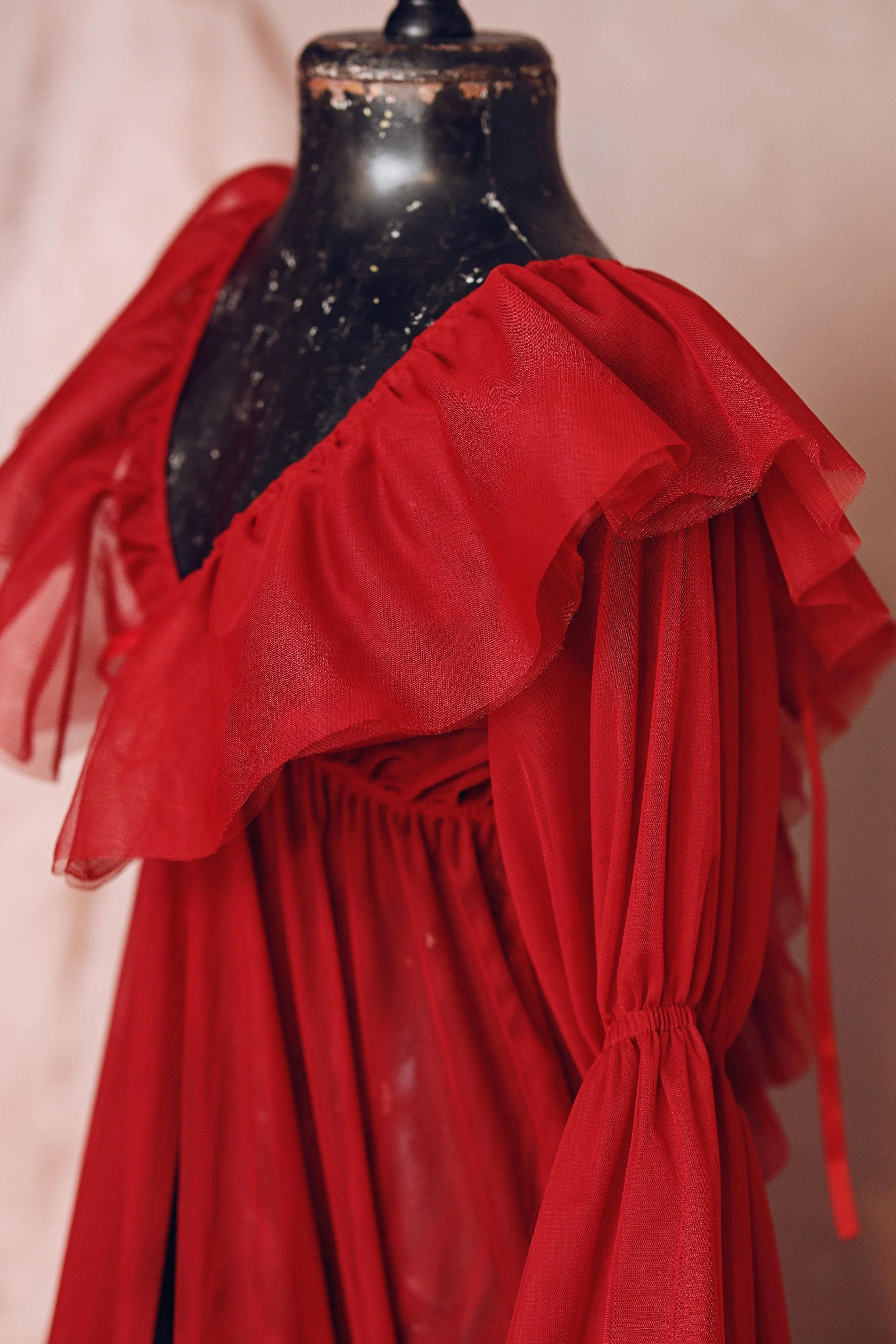 Close up of red tulle robe, showing dramatic tulle shoulders