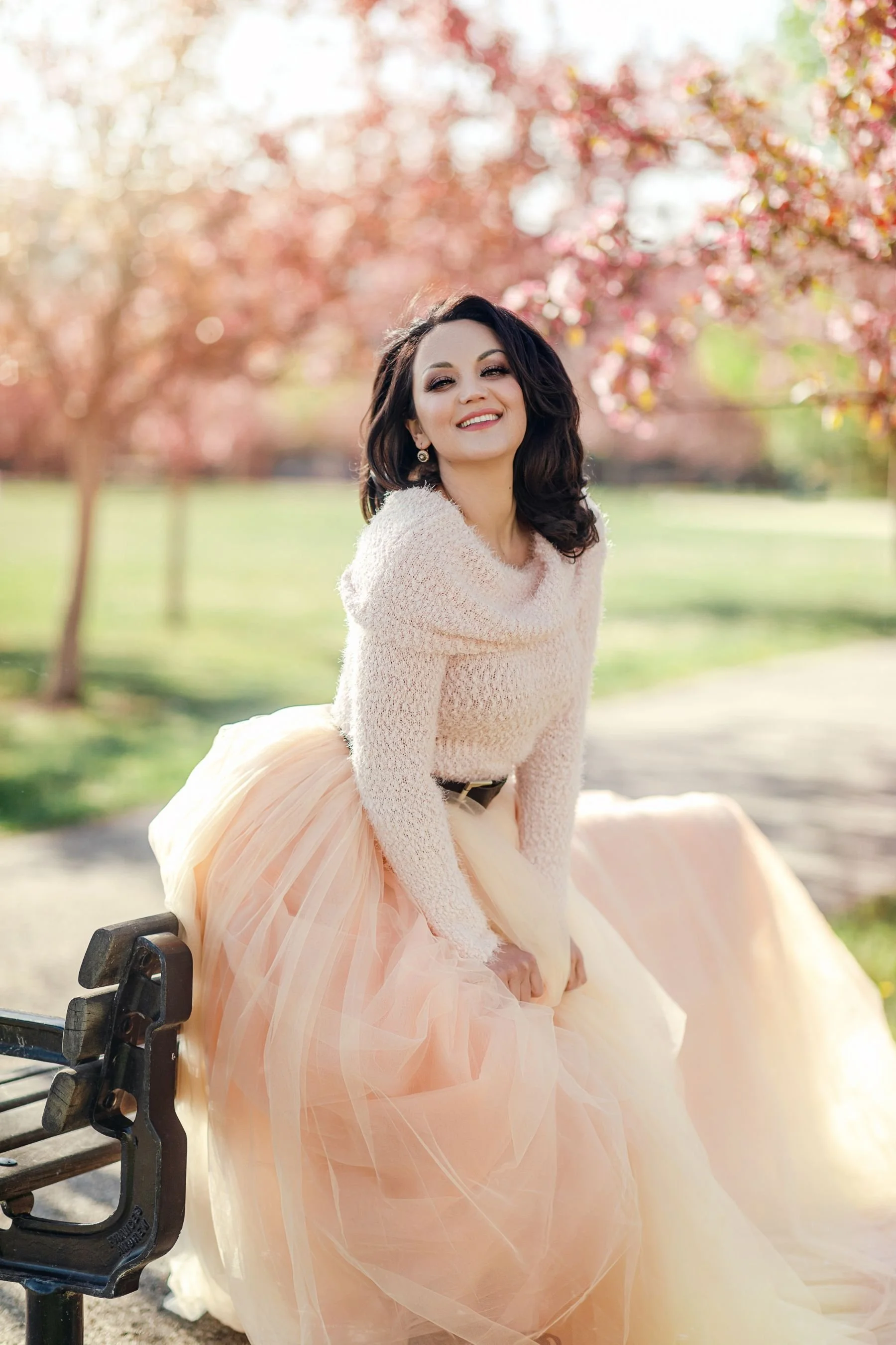 A woman wearing a light peach tulle skirt outfit in an outdoor spring photoshoot in Calgary