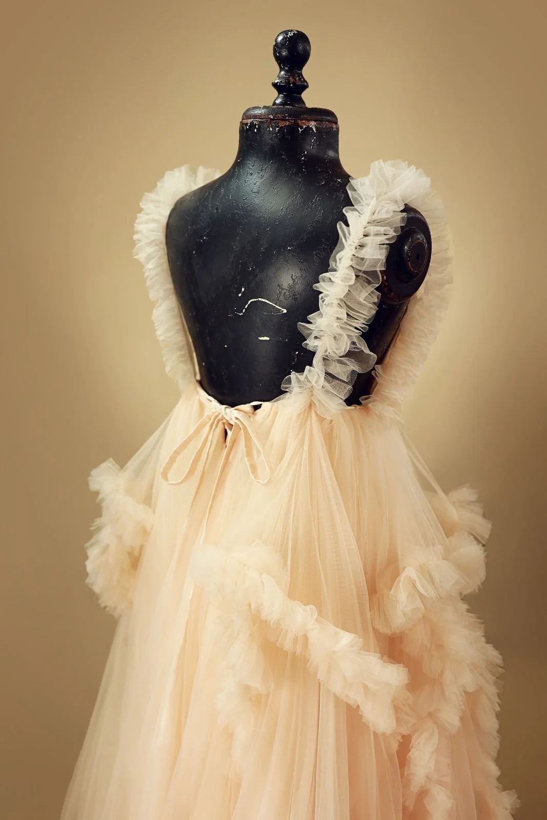 Back view of golden tulle rental gown, featuring open back design