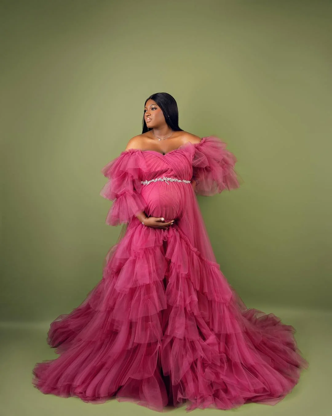 Pregnant woman wearing a pink layered shoulderless tulle gown with silver jewellery belt