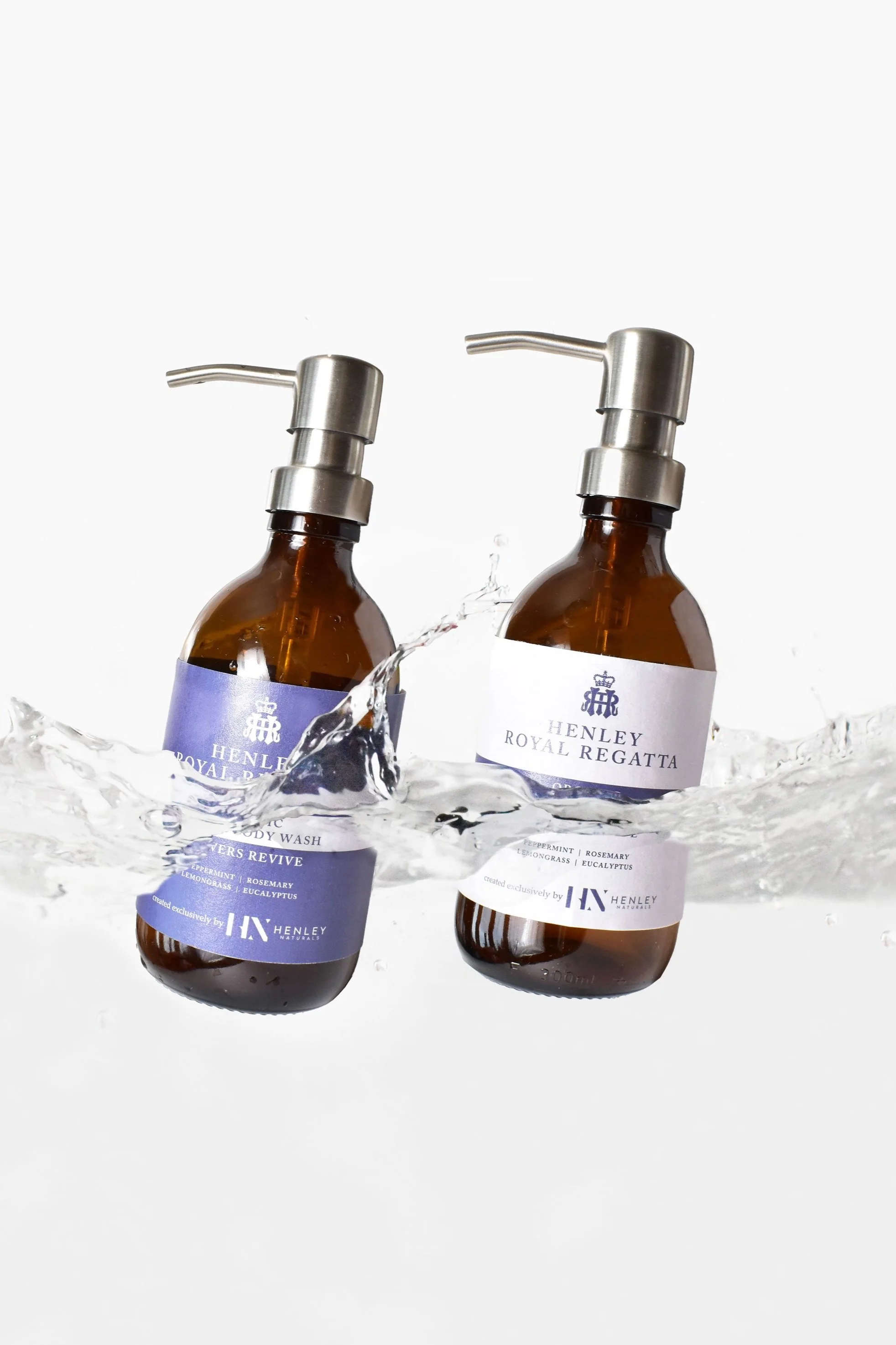 Two Henley Royal Regatta liquid soap dispensers with stainless steel pumps, splashed with water, on a white background.