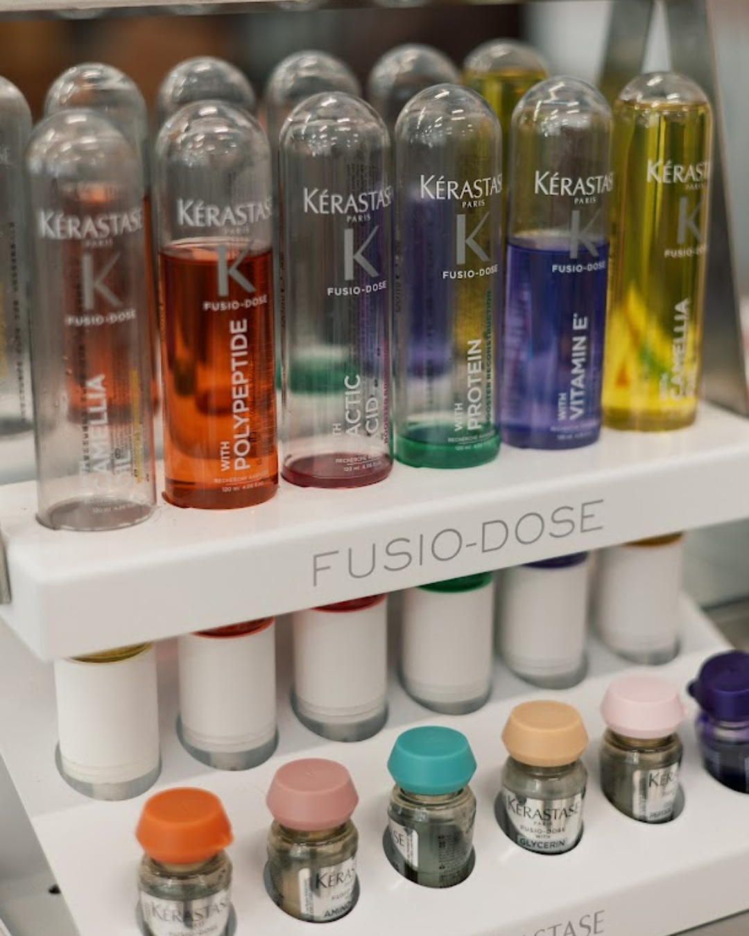 A close-up of a Kérastase Fusio-Dose hair treatment station featuring various specialized formulas.