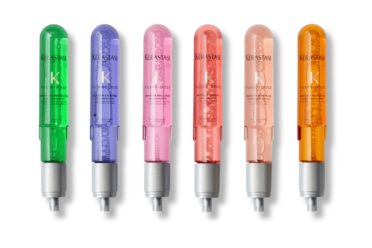 A row of colorful Kérastase Fusio-Dose hair treatment boosters in green, purple, pink, orange, and gold for customized hair care.