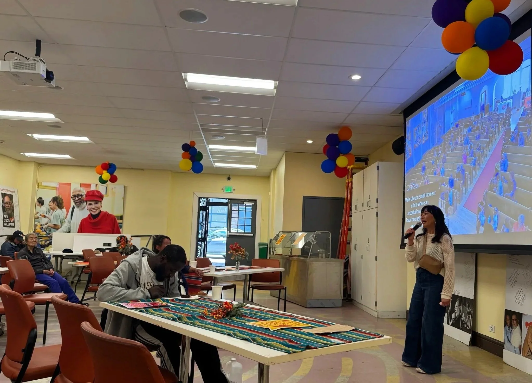 Woman holding a microphone, speaking to a group. (Copy)