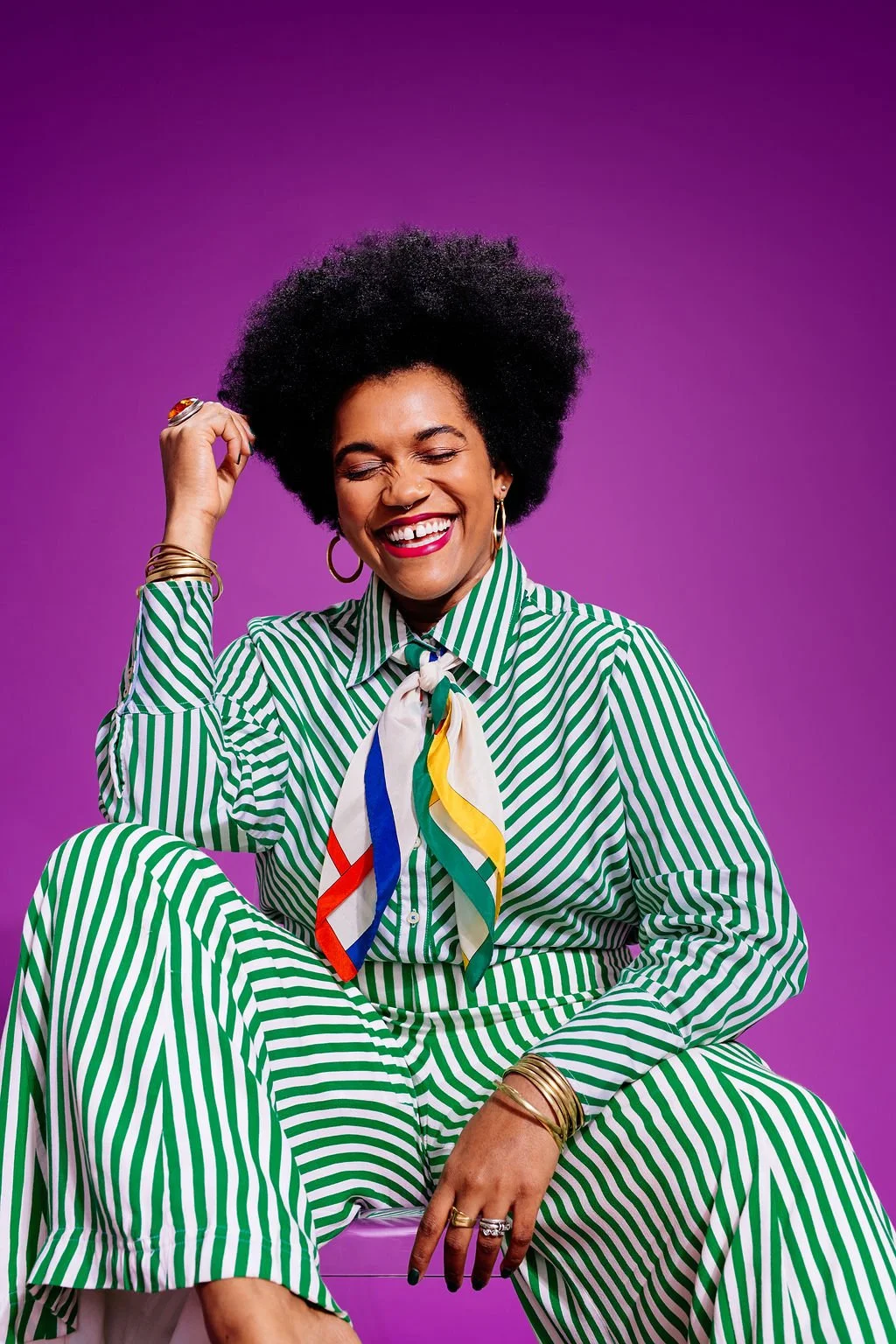 Woman sitting in a striped outfit laughing