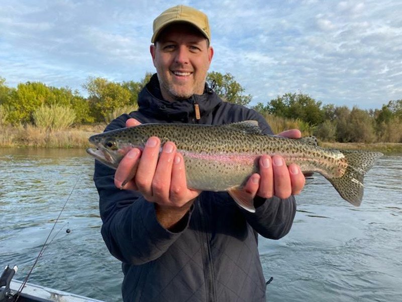 Man happily catches trout after trout fishing with fishing guide in Redding, California