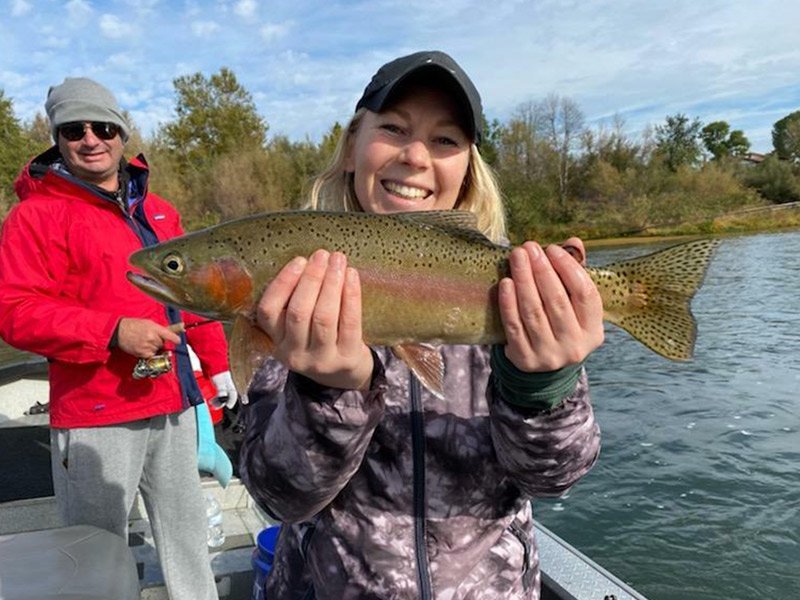 Woman happily catches trout after trout fishing with fishing guide in Redding, California