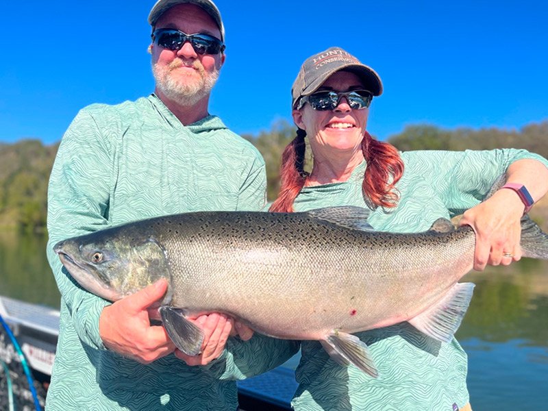 Man and woman catch a King Salmon fish on a fishing trip with fishing guide in California