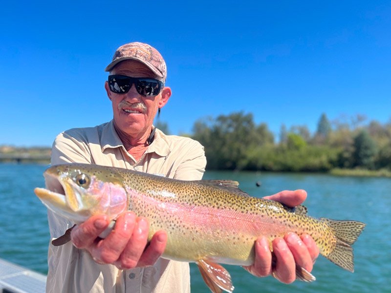 man holding trout he caught on the sacramento river with a fishing guide
