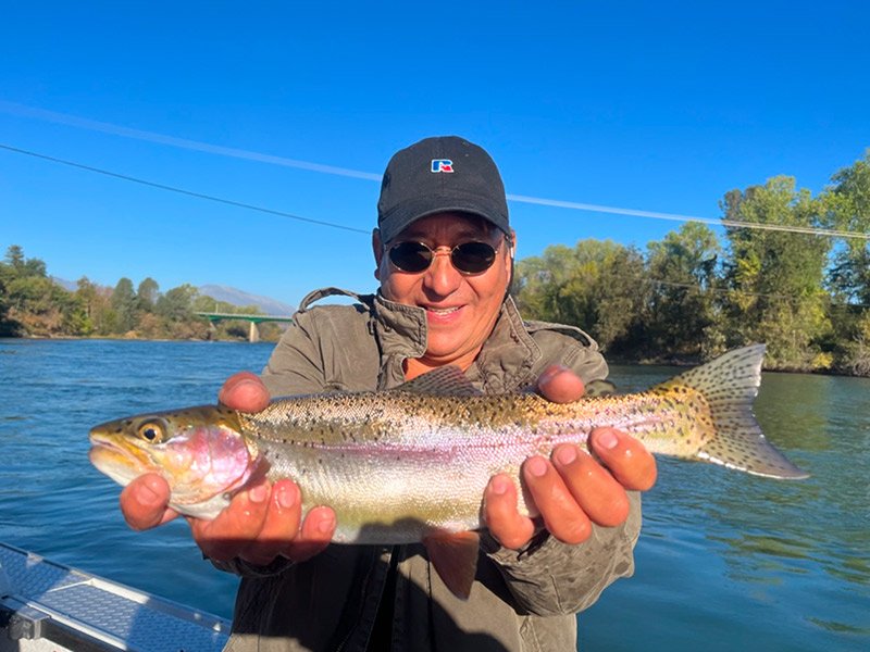 man holding trout he caught on the Sacramento river with a fishing guide