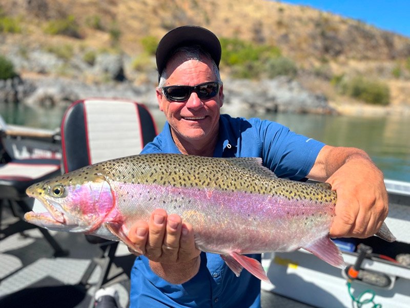 happy man holding trout he caught on the Sacramento river with a fishing expert