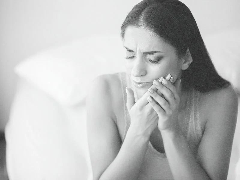 A young woman with severe tooth pain holding her hands to her cheek